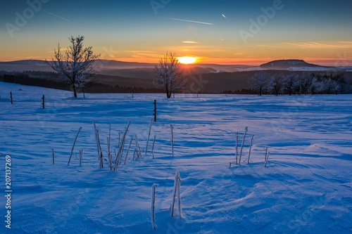 Sonnenuntergang im goldenen Sonnenlicht über dem winterlichen Erzgebirge. Blick zum Scheibenberg, Fichtelberg und Keilberg.