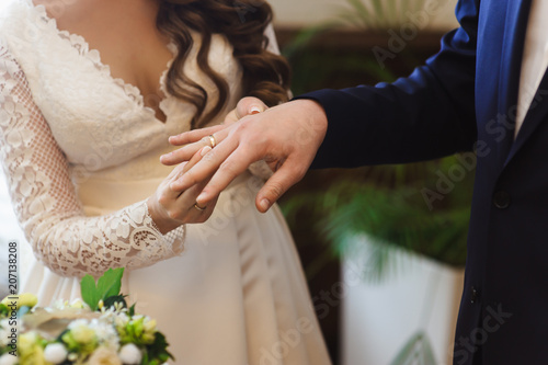 Hands of groom and bride at wedding day. Bridal couple hugging. Wedding bouquet at background. Wedding love and family concept close up macro photo with selective focus photo