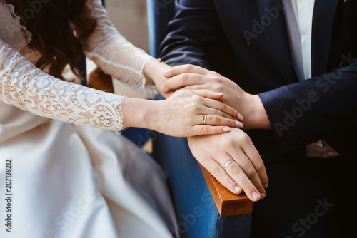 Hands of groom and bride at wedding day. Bridal couple hugging. Wedding bouquet at background. Wedding love and family concept close up macro photo with selective focus photo