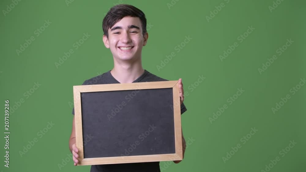 Young handsome Iranian teenage boy against green background Young handsome Iranian teenage boy against green background