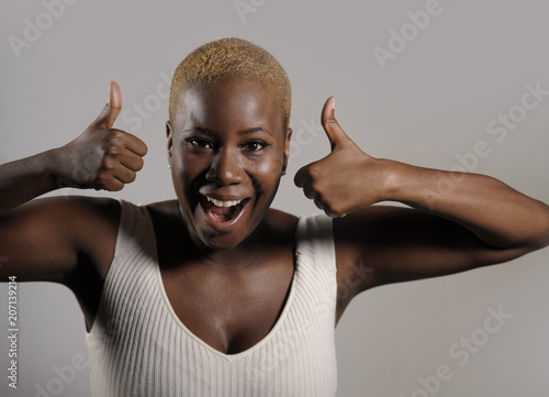 young beautiful and happy black afro American woman smiling giving ok thumb up sign looking positive and playful in cool exotic shaved head hair style
