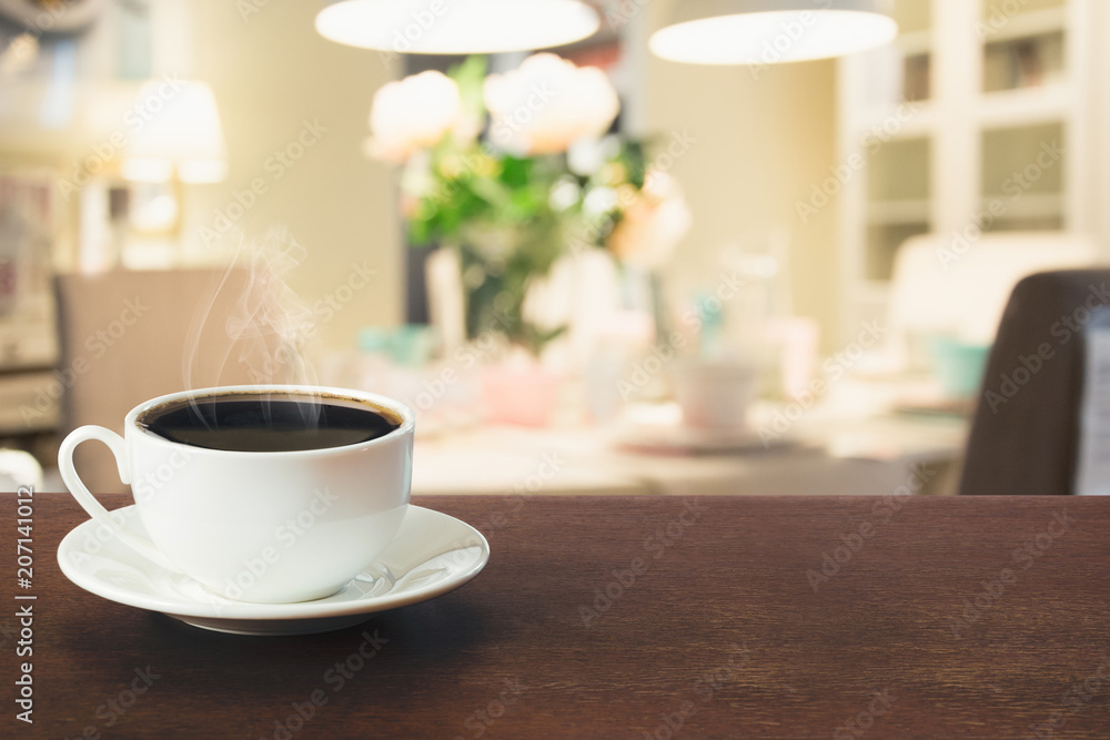 Cup of black coffee on wooden tabletop in blurred modern kitchen or cafe. Close up. Indoor.