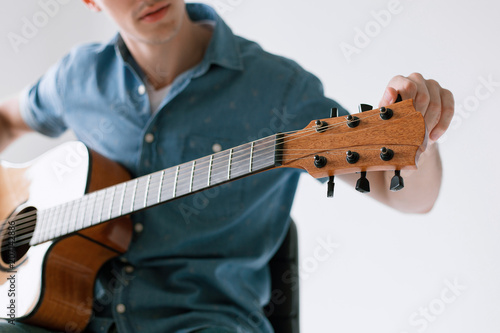 Handsome and cheerful guy musician in a shirt playing guitar