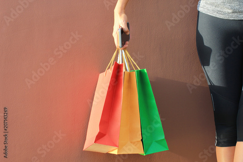 young woman hand holding smartphone and shopping bags with standing on red background