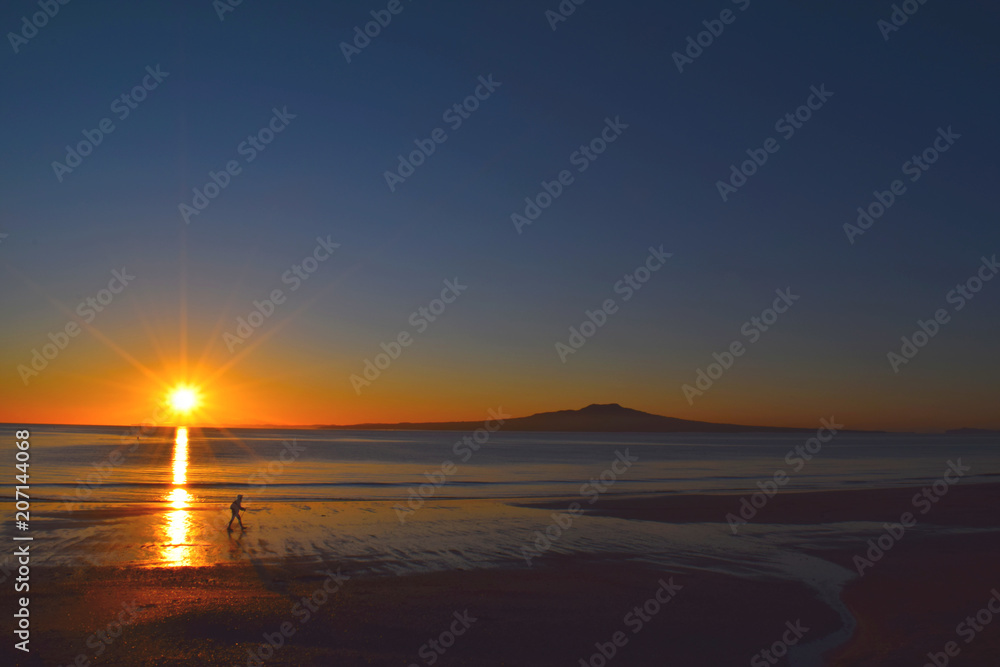 man walking alone in the beach, sunset in the beach, Auckland New Zealand.