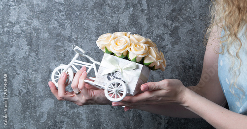 Wedding handmade decor: The girl holds a small bouquet of roses in her hands in a decorative box in the form of a bicycle. Close-up of hands.