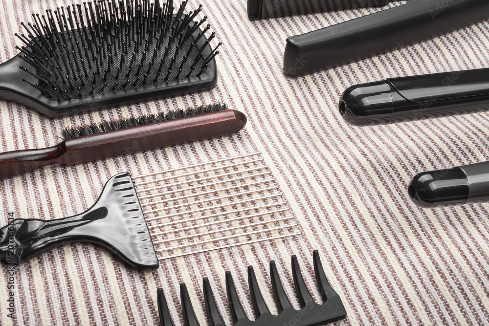 set of various hair straightening tools with metal plates lying oppositely to row of combs on a grey striped background. concept of healthy care of hair set of various hair straightening tools with metal plates lying oppositely to row of combs on a grey striped background. concept of healthy care of hair