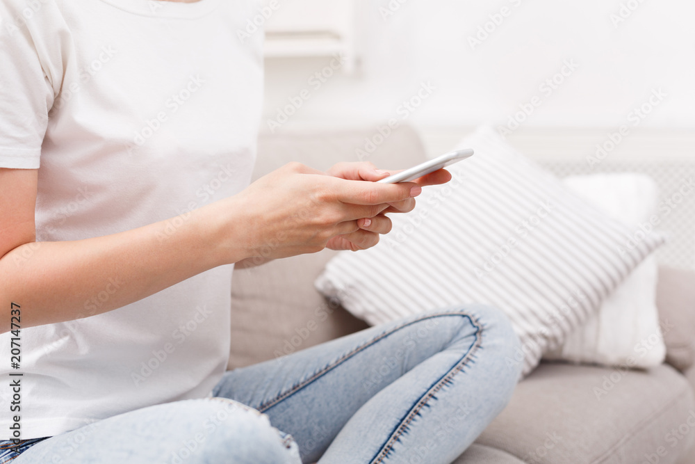 Unrecognizable girl with smarphone sitting on the sofa Unrecognizable girl with smarphone sitting on the sofa