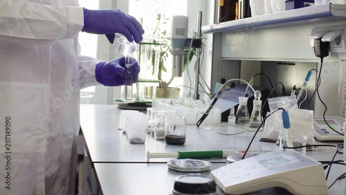 Hands of the scientist in laboratory pouring water in graduated cylinder and adding it to the samples of the soil