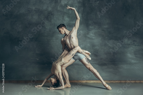 The young modern ballet dancers posing on gray studio background © master1305