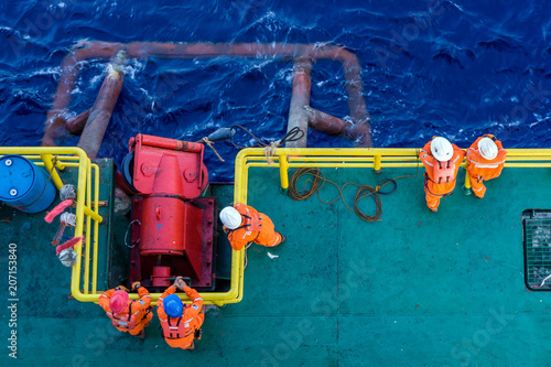 Offshore workers working together during anchor handling job on a construction barge at oil field