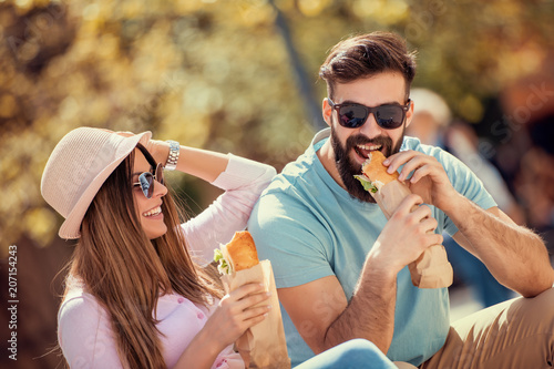 Couple eating sandwich outdoors
