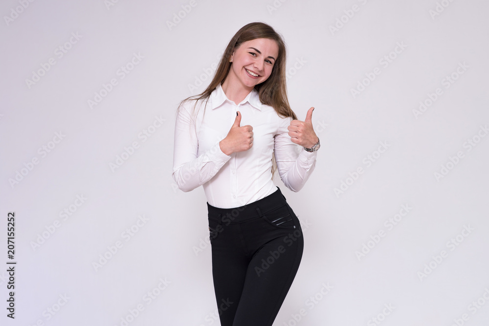 portrait of a beautiful brunette girl on a white background in a white shirt showing on a product. portrait of a beautiful brunette girl on a white background in a white shirt showing on a product.