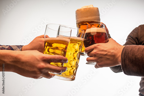 hands with mugs of beer toasting creating splash isolated on white background