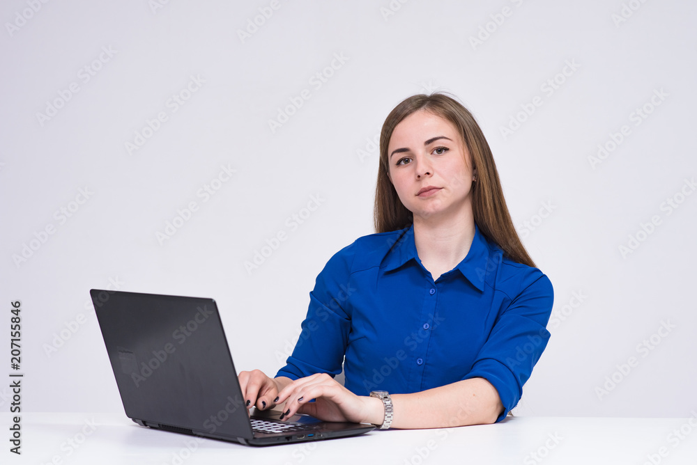 portrait of beautiful brunette girl on white background sitting at table with laptop, notebook. portrait of beautiful brunette girl on white background sitting at table with laptop, notebook.
