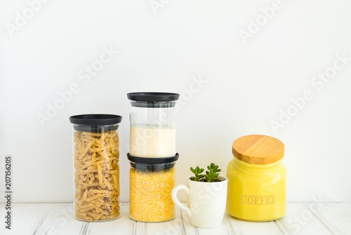 Pasta and cereals in glass jars on white background. Organized kitchen and healthy eating concept