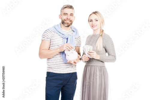 Portrait of young couple putting money in piggy bank isolated on white background