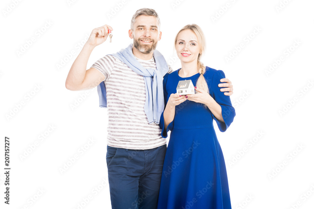 Happy couple holding house model and keys, standing isolated over white background Happy couple holding house model and keys, standing isolated over white background