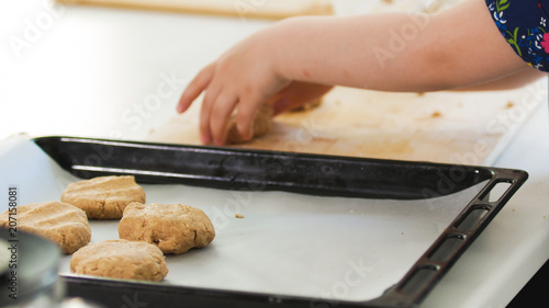 Preschool girl baker puts homemade cookies on a baking sheet