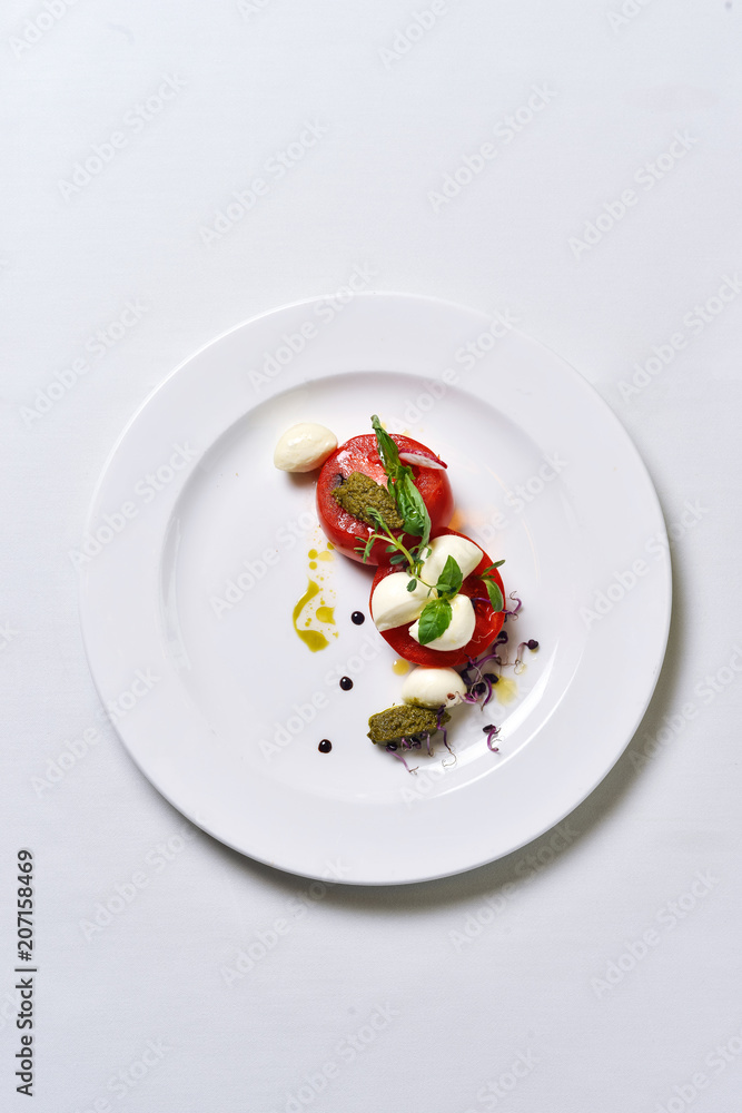 Mozzarella with tomatoes salad on a white plate isolated. Mozzarella with tomatoes salad on a white plate isolated.