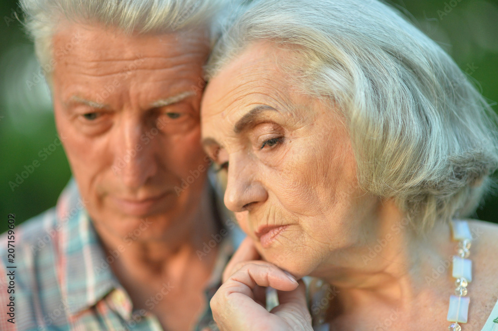 Sad senior couple in autumn park