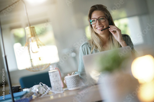 Business girl in home-office using headset