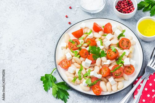 White bean tomato salad on concrete background. Selective focus, space for text.