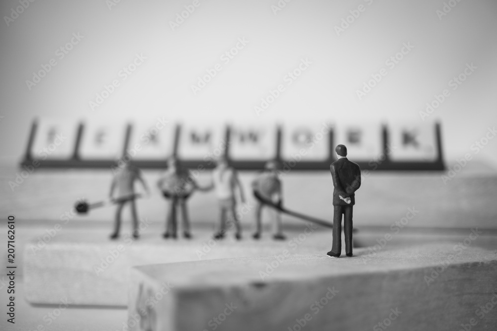 Miniature people, chief and engineer team standing on wooden block using as industry and business concept - Black and white filter Miniature people, chief and engineer team standing on wooden block using as industry and business concept - Black and white filter