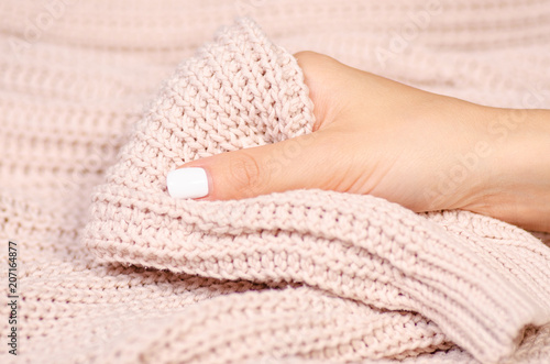 Beige knitted sweater female hand macro blur background