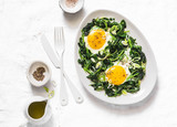 Fried organic farm eggs with spinach - healthy breakfast on a light background, top view