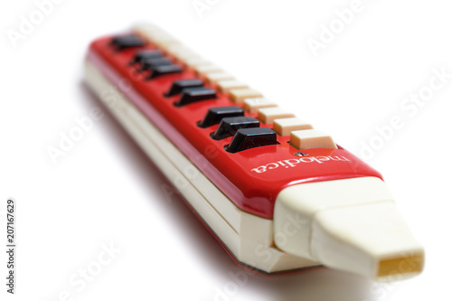 Closeup of old german vintage red melodica on white background photo