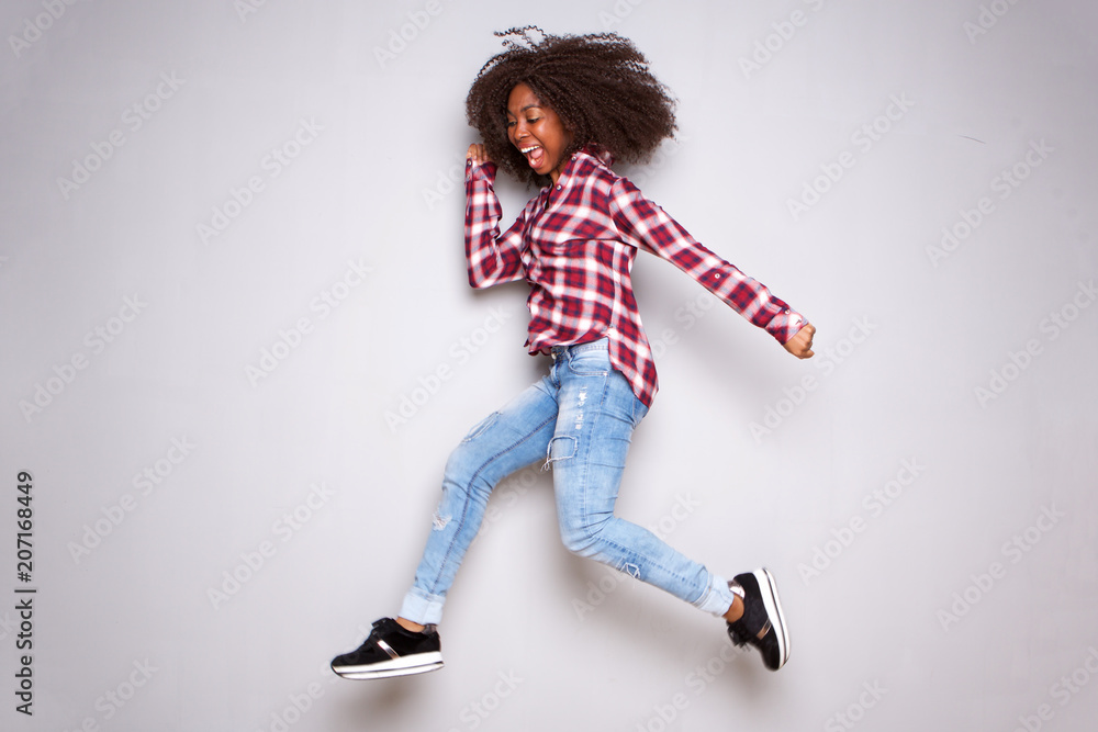 Full length happy young african woman jumping over white background