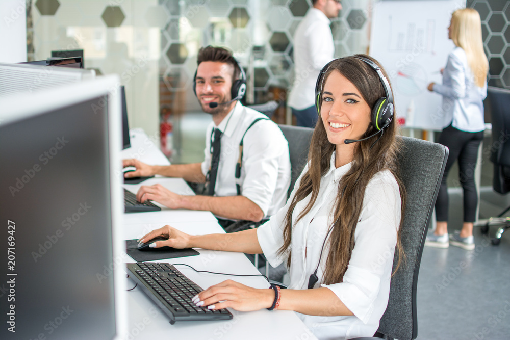 © Bojan - Beautiful and cheerful young woman and man telephone operators with headsets working on desktop computer in customer service call support helpline business center © Bojan - Beautiful and cheerful young woman and man telephone operators with headsets working on desktop computer in customer service call support helpline business center