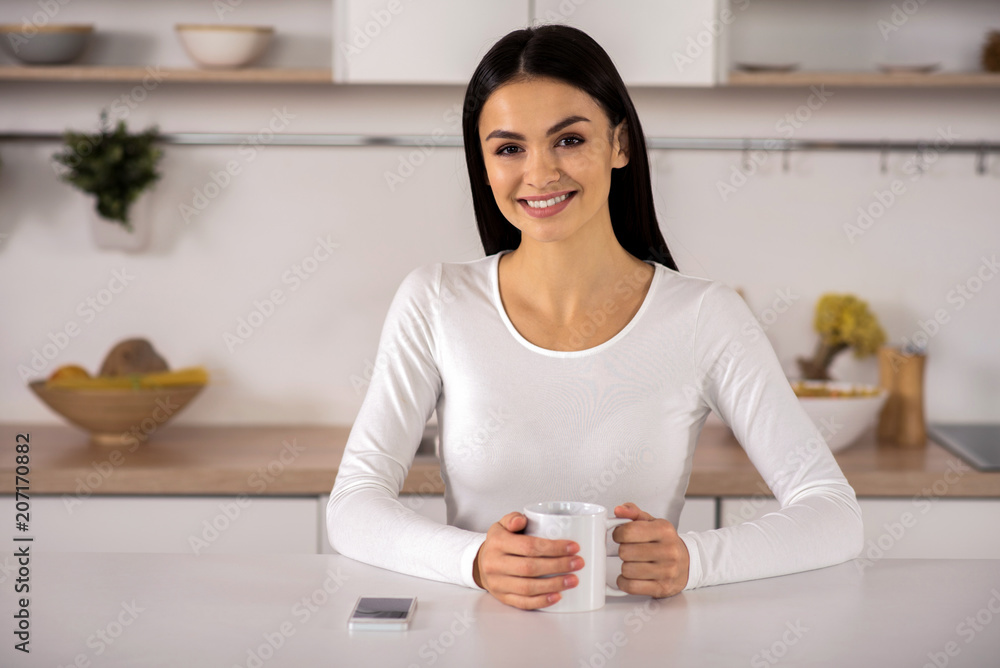 Glad smiling woman drinking tea in the kitchen Glad smiling woman drinking tea in the kitchen