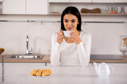 Delighted woman drinking tea in the kitchen