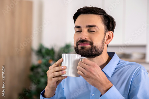 Delighted businessman smelling his coffee