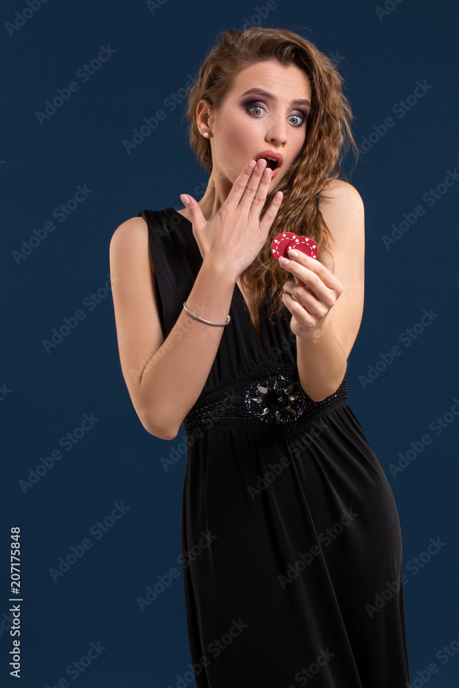Portrait of the female gambler at the casino keeping poker chips in the hand