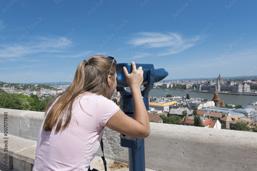 Girl looking through coin operated binocular viewer at Hungarian Parliament in Budapest