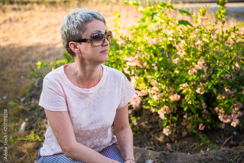 Portrait of a girl in a blooming garden. A woman is walking in the summer in the park. Happy middle-aged woman  