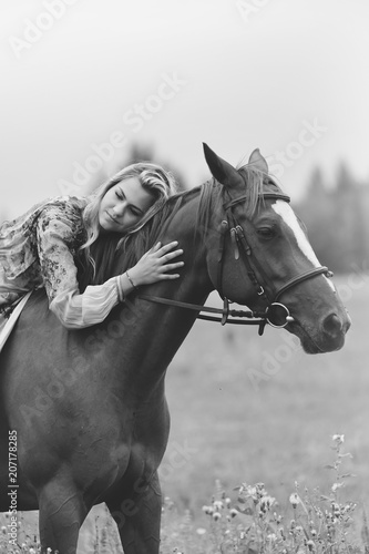 Young woman sits on a horse in a summer meadow © sergo321