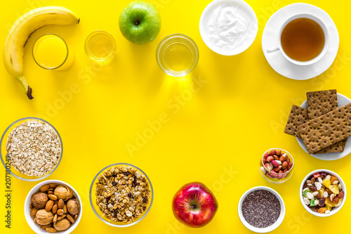 Ideas of healthy hearty breakfast for sportsmen. Fruits, oatmeal, yogurt, nuts, crispbreads, chia on yellow background top view copy space