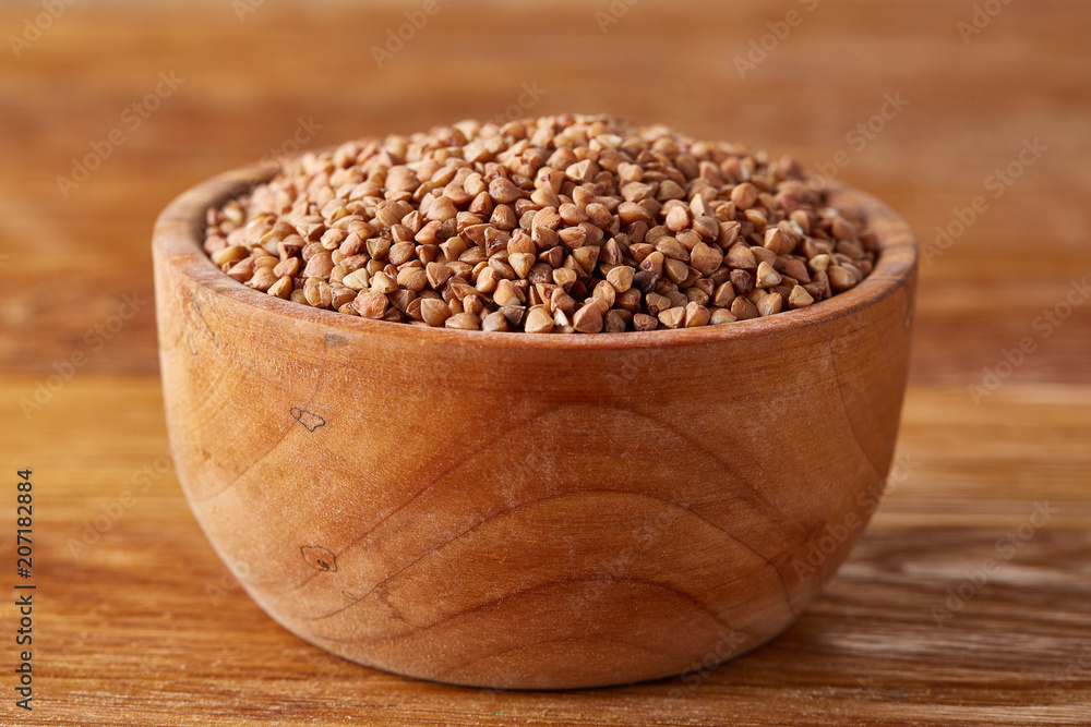 Bowl full of buckwheat grains on rustic wooden table, close-up, selective focus, shallow depth of field. Bowl full of buckwheat grains on rustic wooden table, close-up, selective focus, shallow depth of field.
