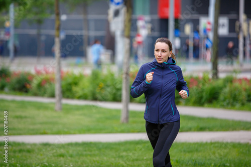 Young woman running in european city park. Healthy lifestyle concept background