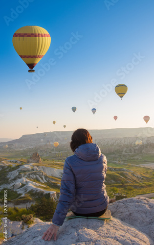 woman on top of Cappadocia hill in early morning sunrise, when balloons fly. Romantic Cappadocia scene, Turkey