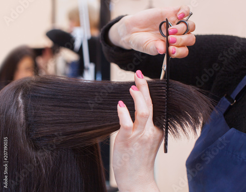 The hairdresser does a haircut with hot scissors of hair to a young girl, a brunette in a beauty salon.