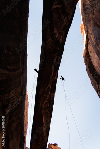 People rappelling off of Morning Glory Arch in Moab, Utah. 