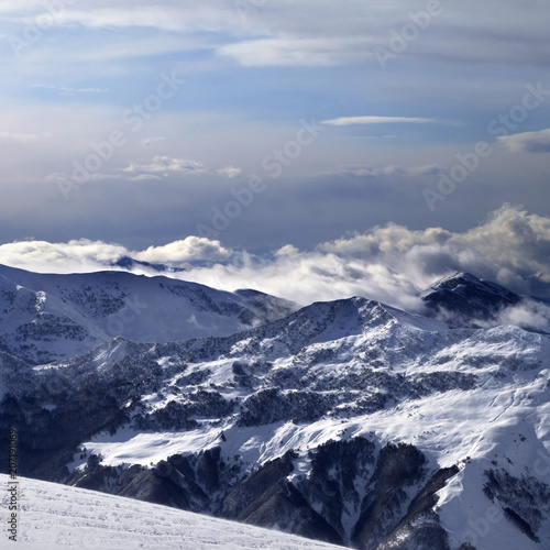 Winter mountains in clouds and ski slope © BSANI