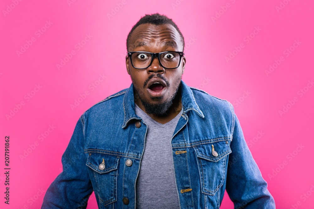 Fototapeta premium African man opened his mouth in surprise standing on a pink background