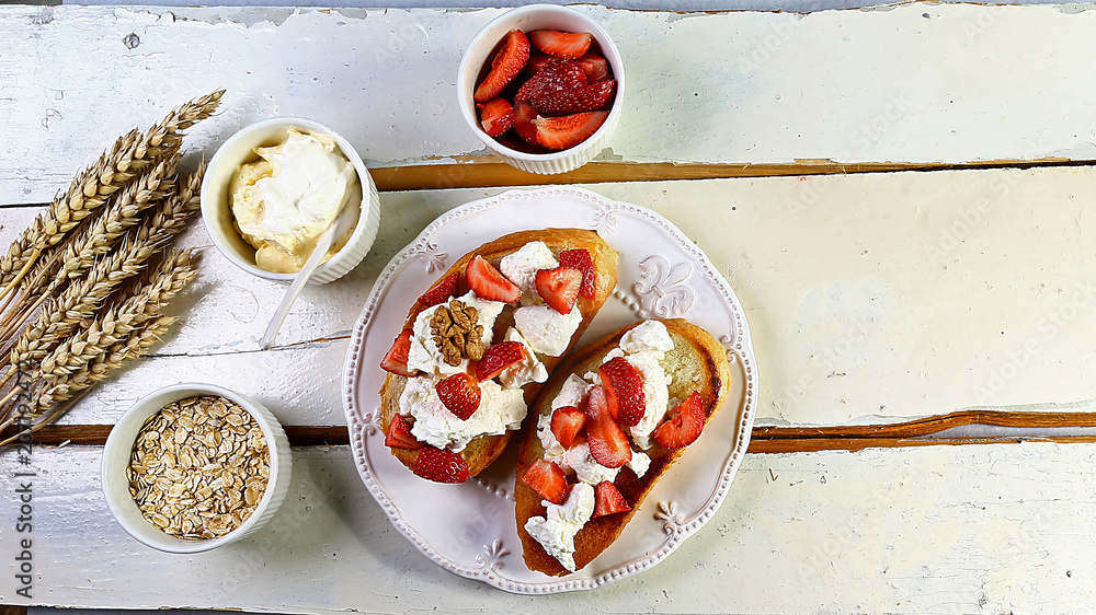 Two toasts or bruschetta with strawberry, nuts and cheese on wooden white rustic background. Top view, flat lay Two toasts or bruschetta with strawberry, nuts and cheese on wooden white rustic background. Top view, flat lay