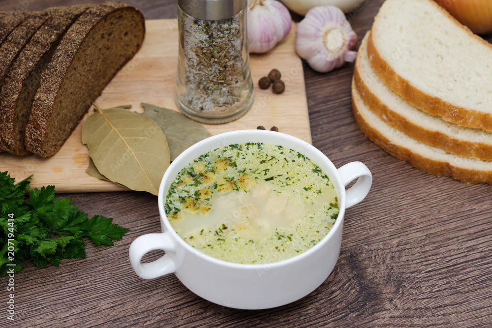 Mushroom soup with croutons in a white dish is on a wooden table. Mushroom soup with croutons in a white dish is on a wooden table.